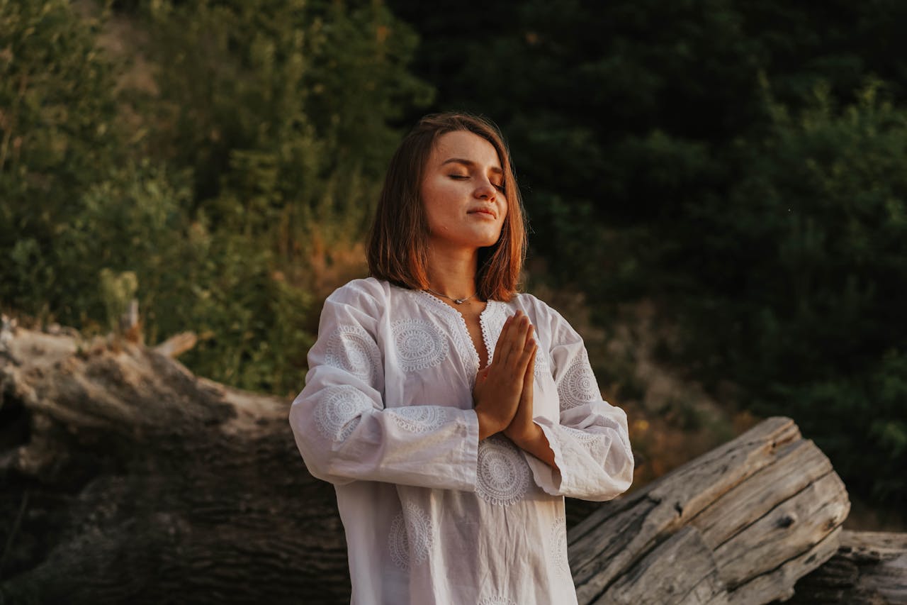 A woman with short hair meditates outdoors, embracing tranquility amidst nature.